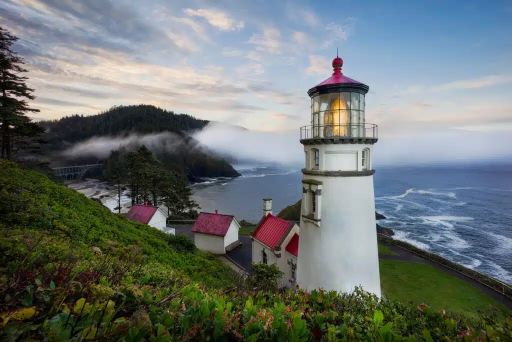 Family road trip ideas for Oregon, Hecate Head Lighthouse. A stunning white lighthouse with red roof perched atop a craggy ocean cliff